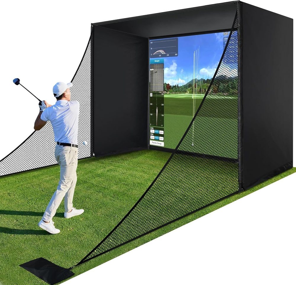 A golfer mid-swing in front of a home golf simulator enclosure and screen