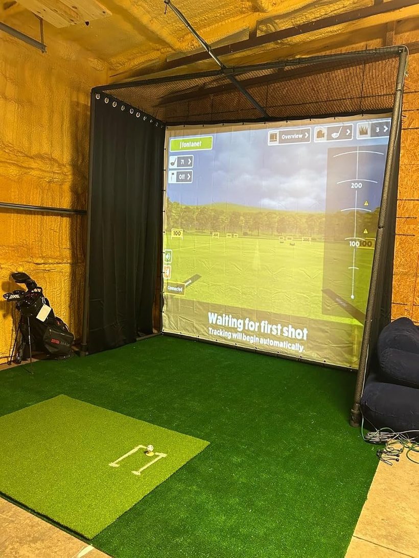 A garage golf simulator build with a cage enclosure, impact screen and hitting mat